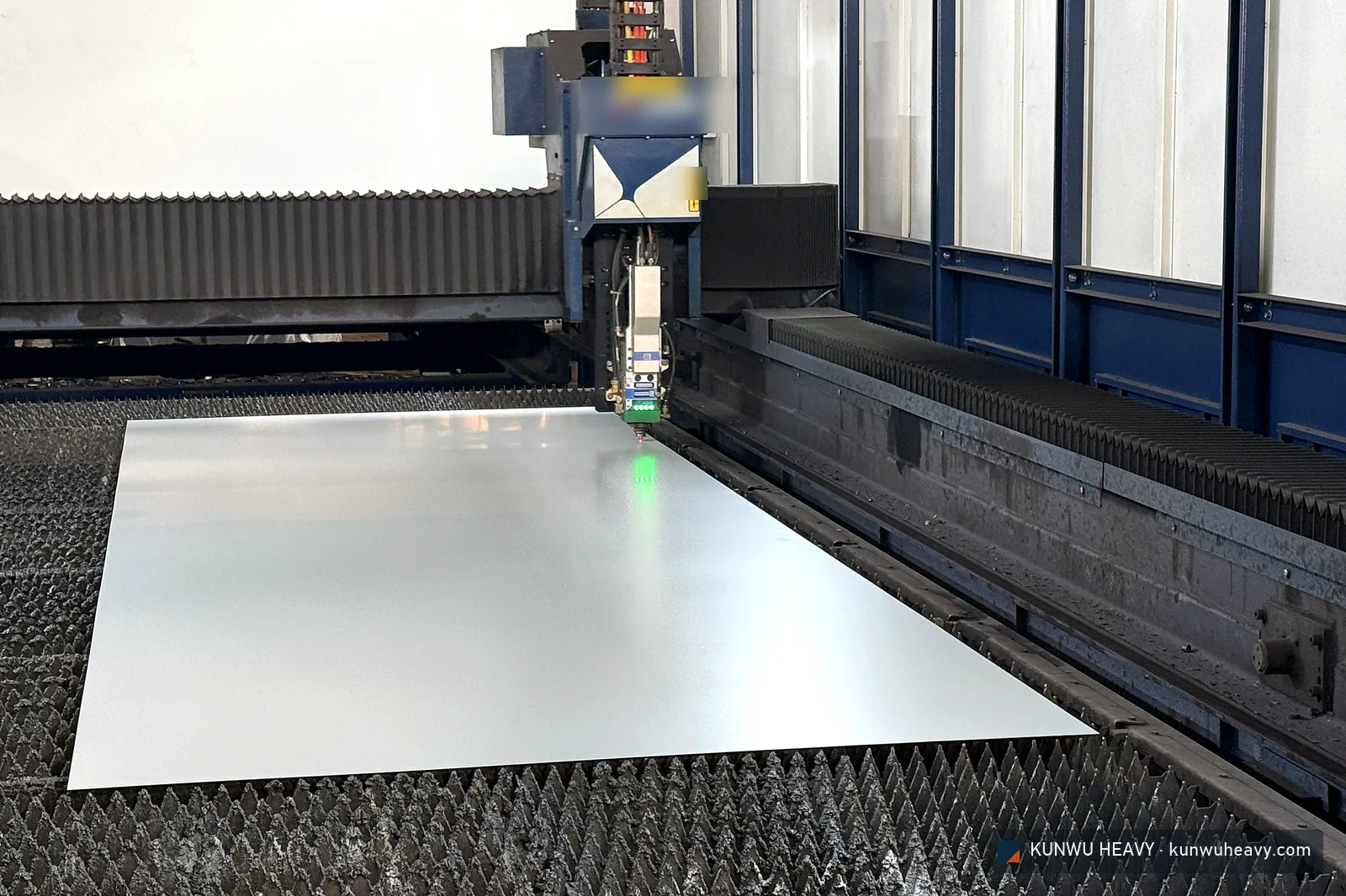 Fiber laser cutting head over a coated steel sheet on the slat bed