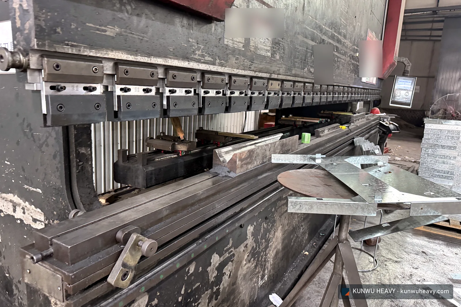 CNC press brake with segmented clamps, folded galvanized parts in front